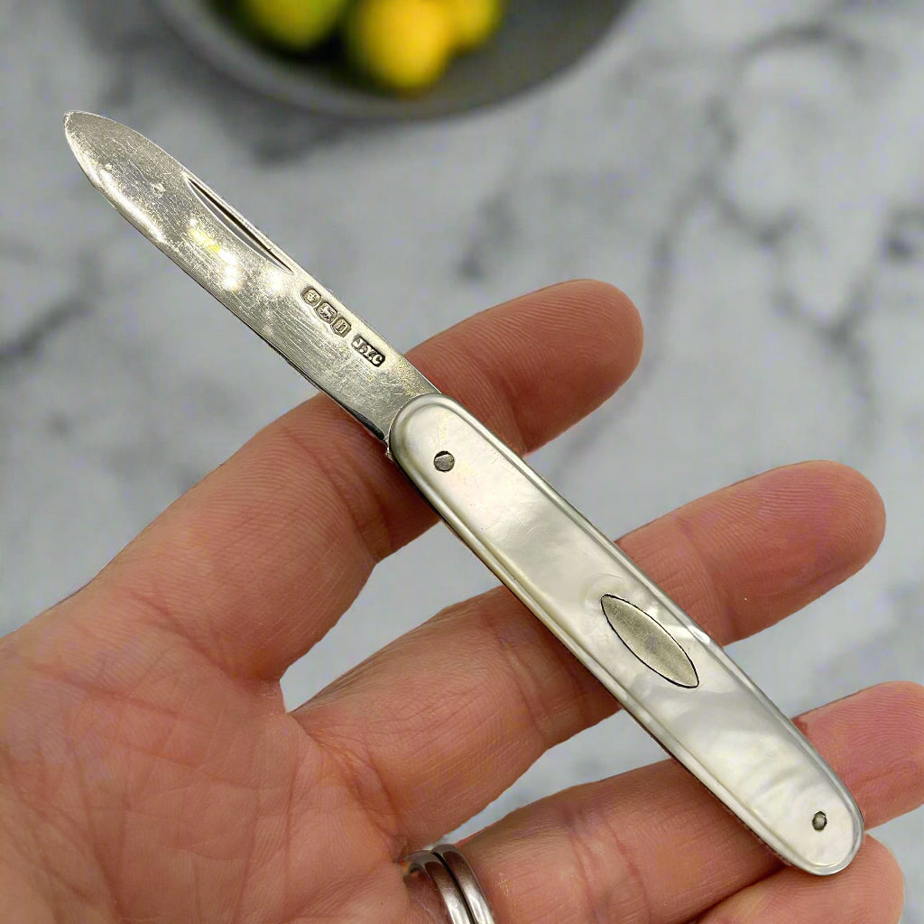 Silver pocket knife held in a hand against a white background