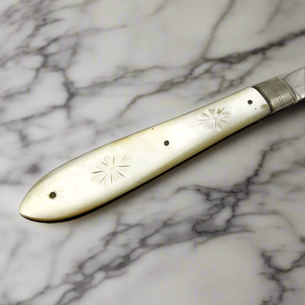 Folding knife with decorative handle on a light marble background