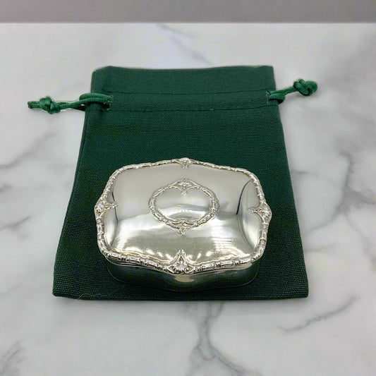 Silver Jewellery box on a green drawstring bag with a marble background
