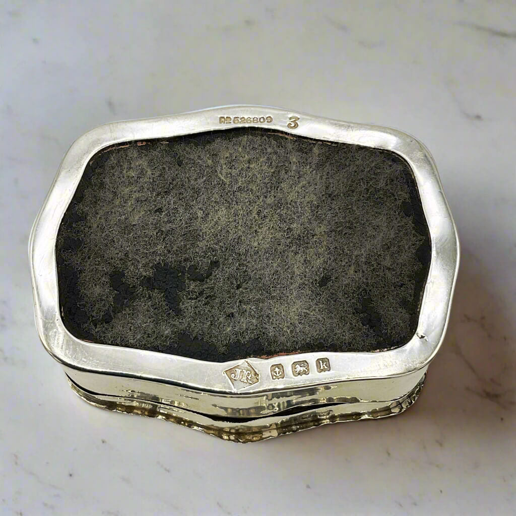Hallmarks on base of silver box on a marble background