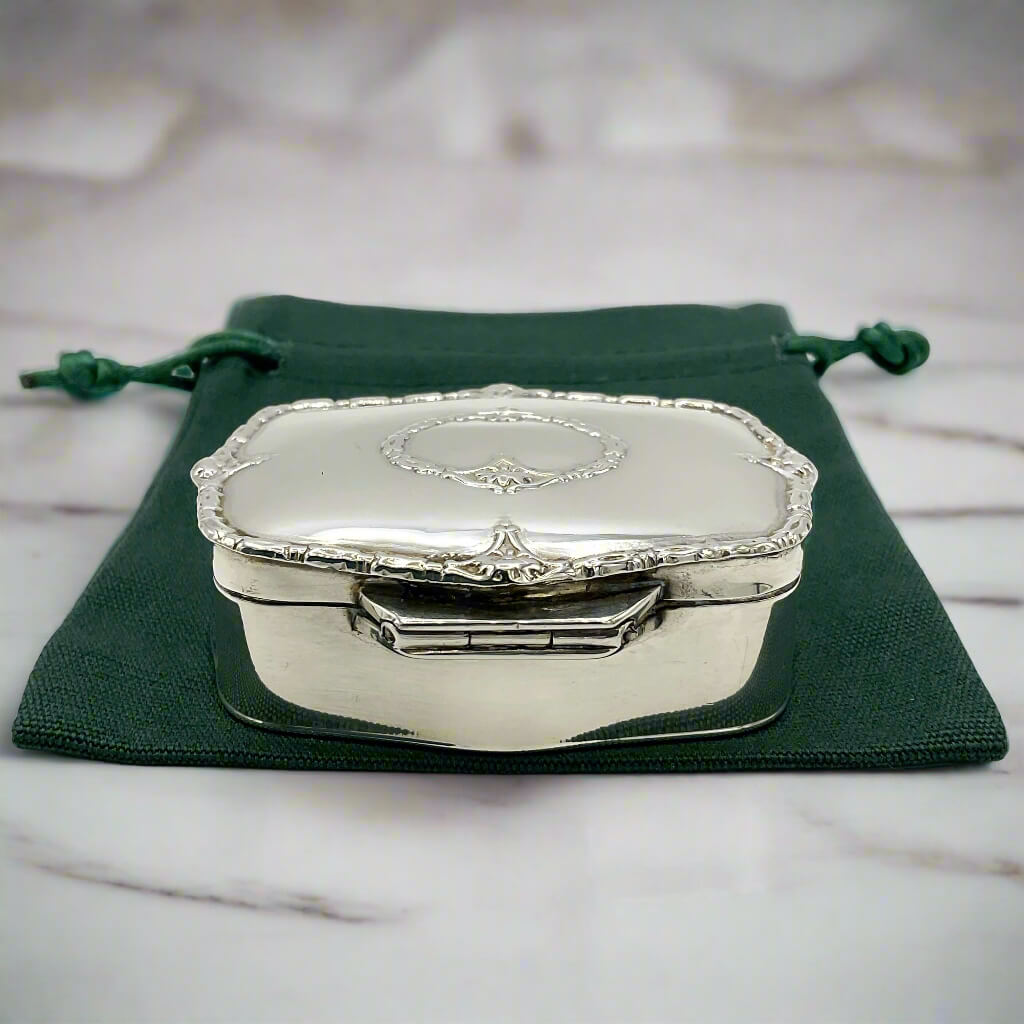 Silver jewelry box on a green fabric pouch with a marble background