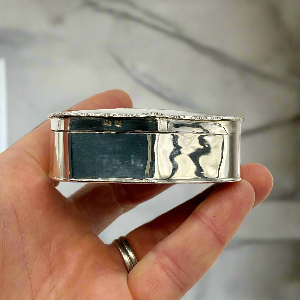 Silver ring box held in a hand against a white background
