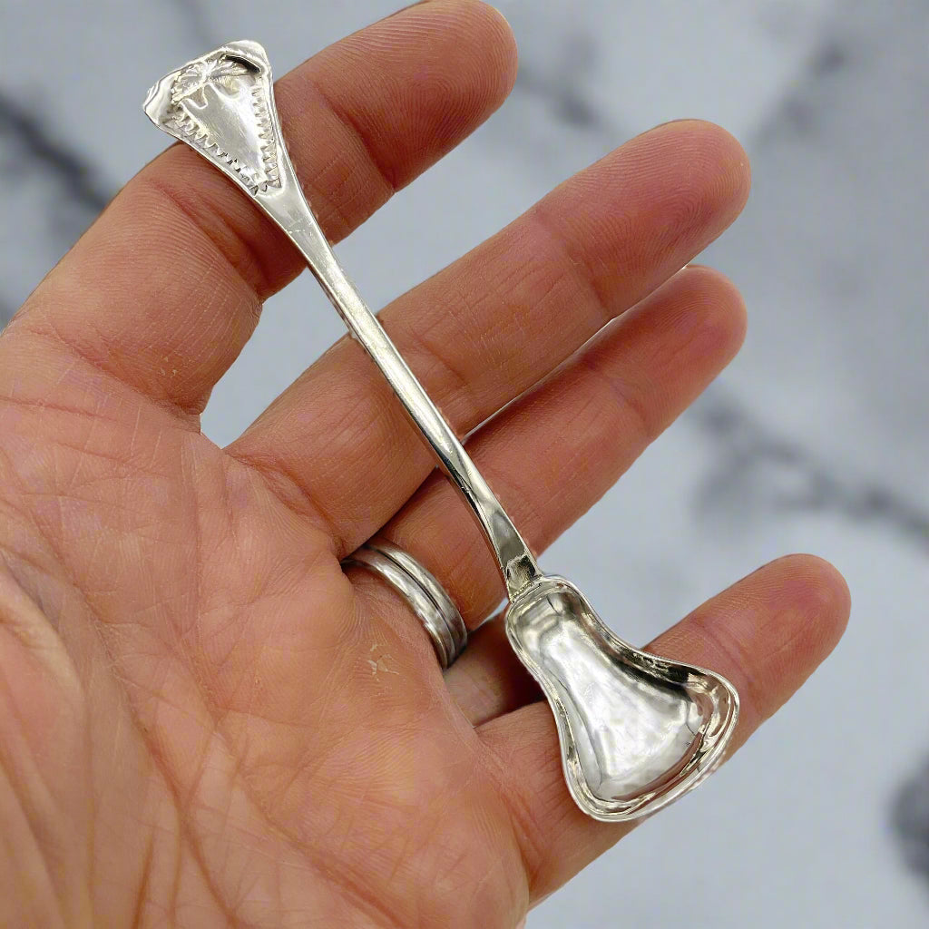 Silver spoon held in a hand against a marble background