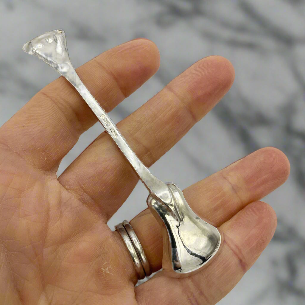 Silver spoon held in a hand against a marble background