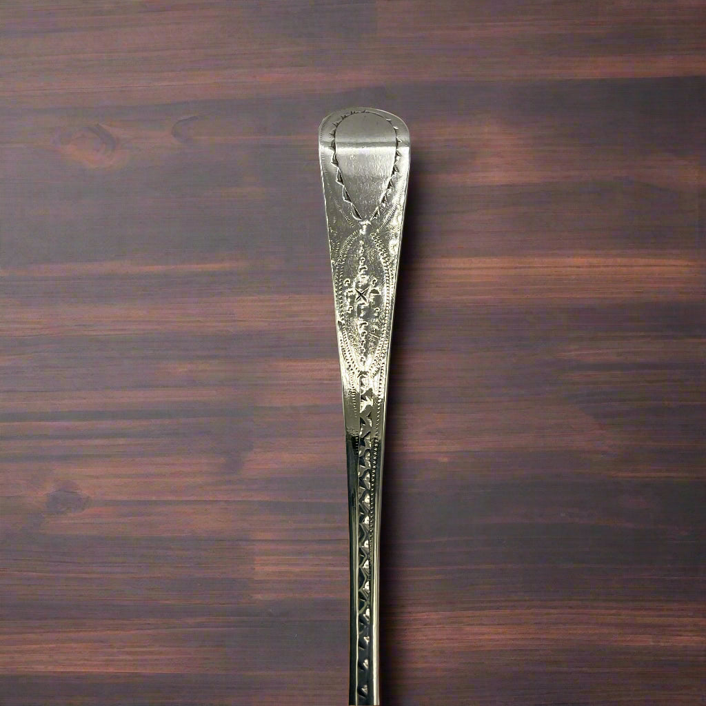 Decorative silver spoon handle on a dark wood table