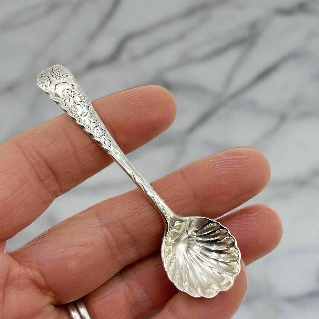 Silver spoon held between fingers against a white background