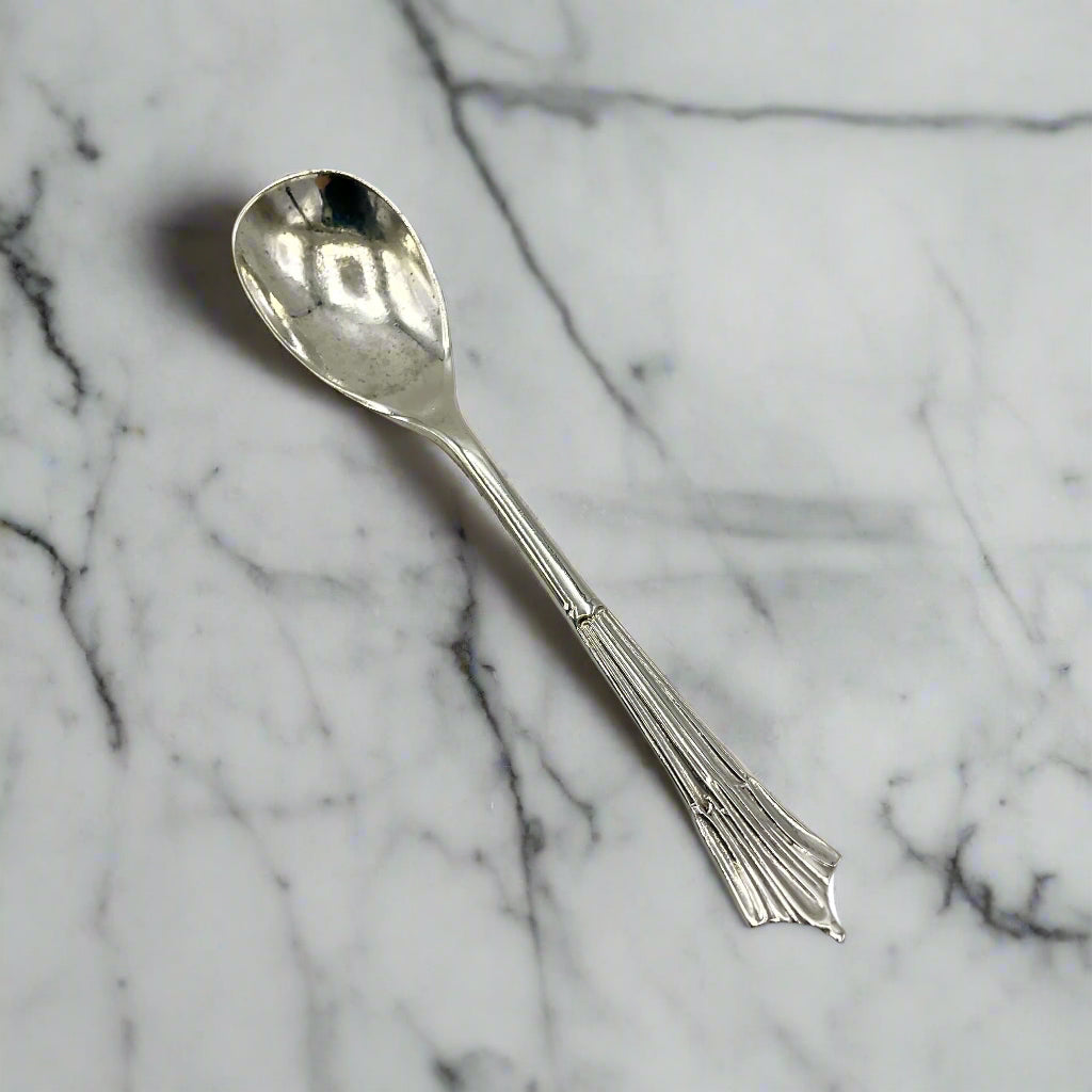 Silver spoon with decorative handle on a marble background