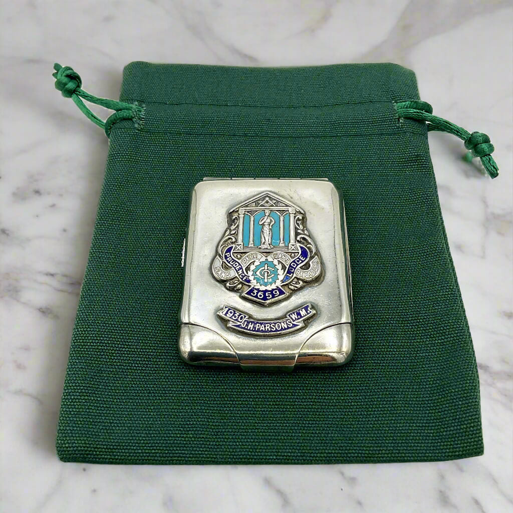 Silver matchbook on a green drawstring pouch with a marble background