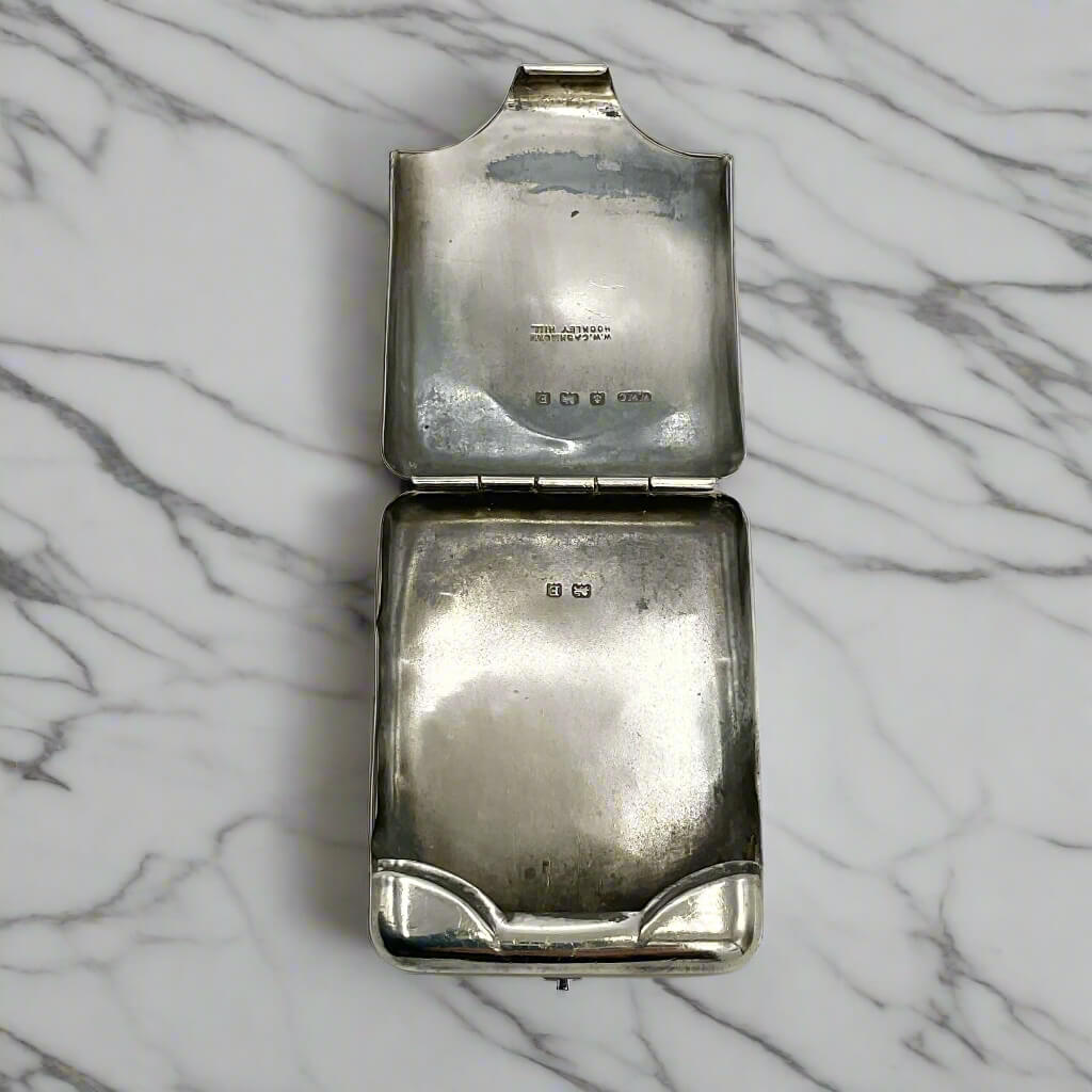 Silver matchbook case open showing the inside with hallmarks on a marble worktop