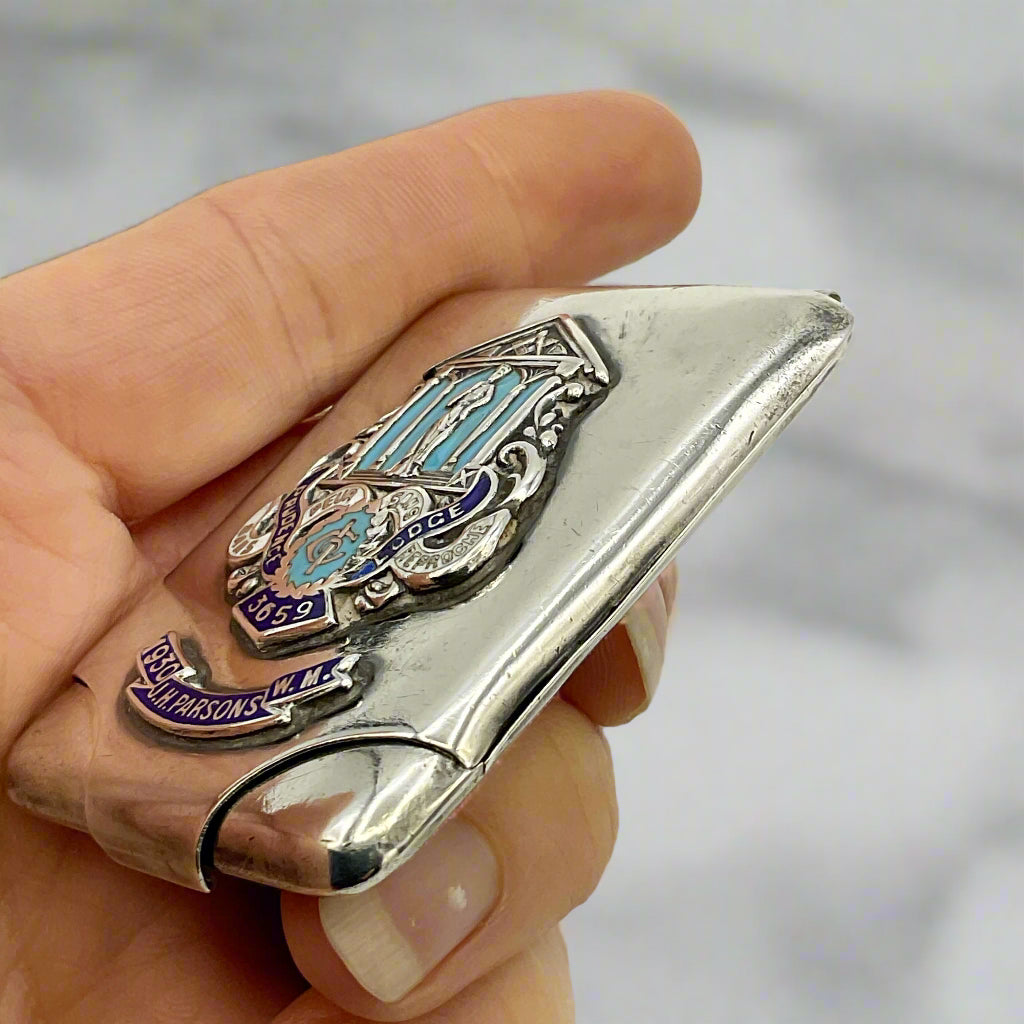 Hand holding a silver and blue decorative silver matchbook case against a marble background