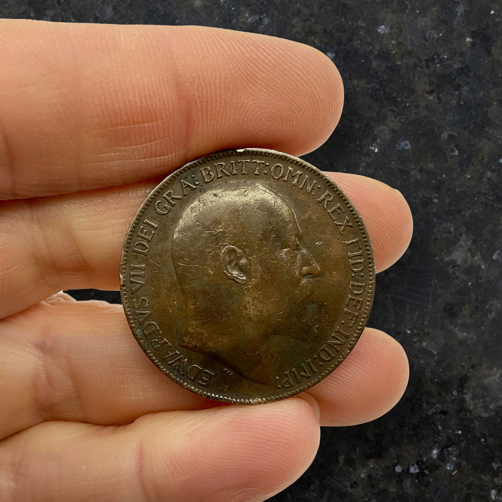 Hand holding an antique coin with King Edward VII on