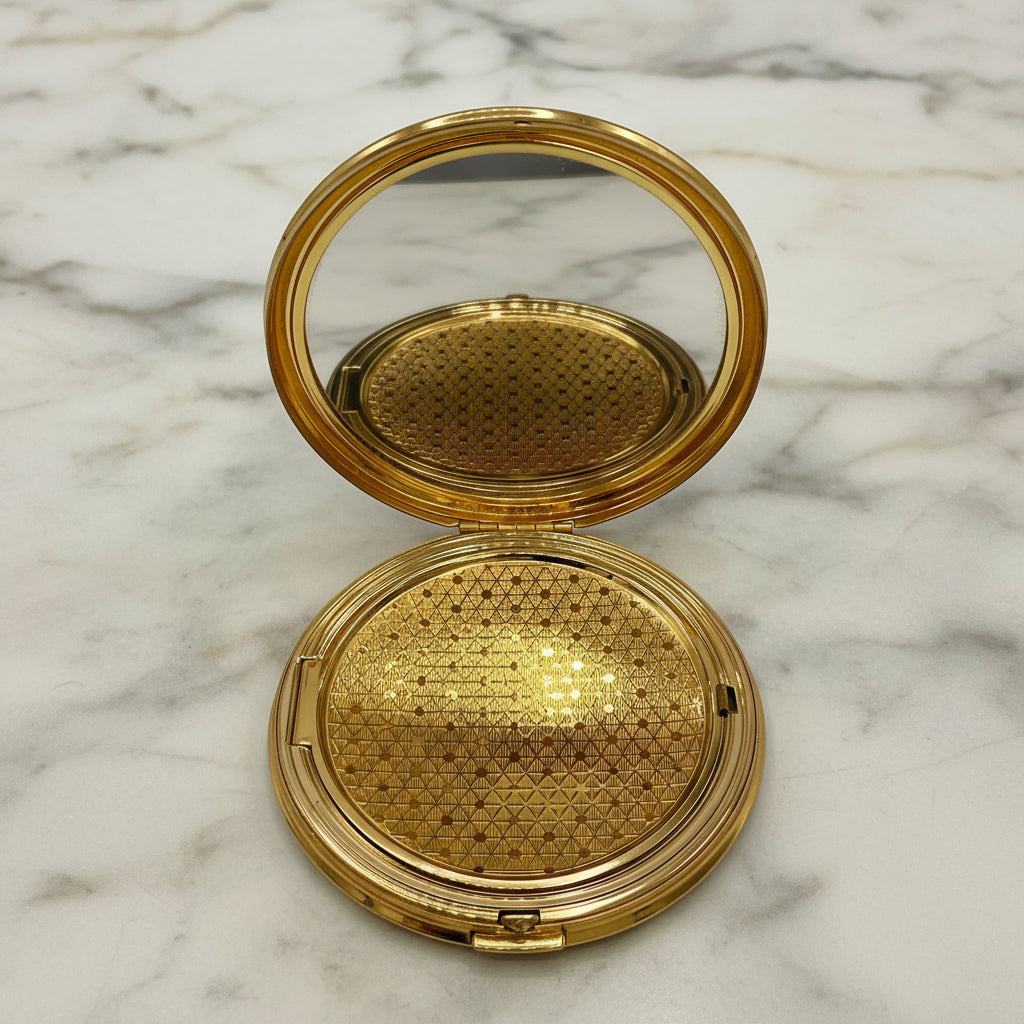 Gold compact mirror with open lid on a marble background