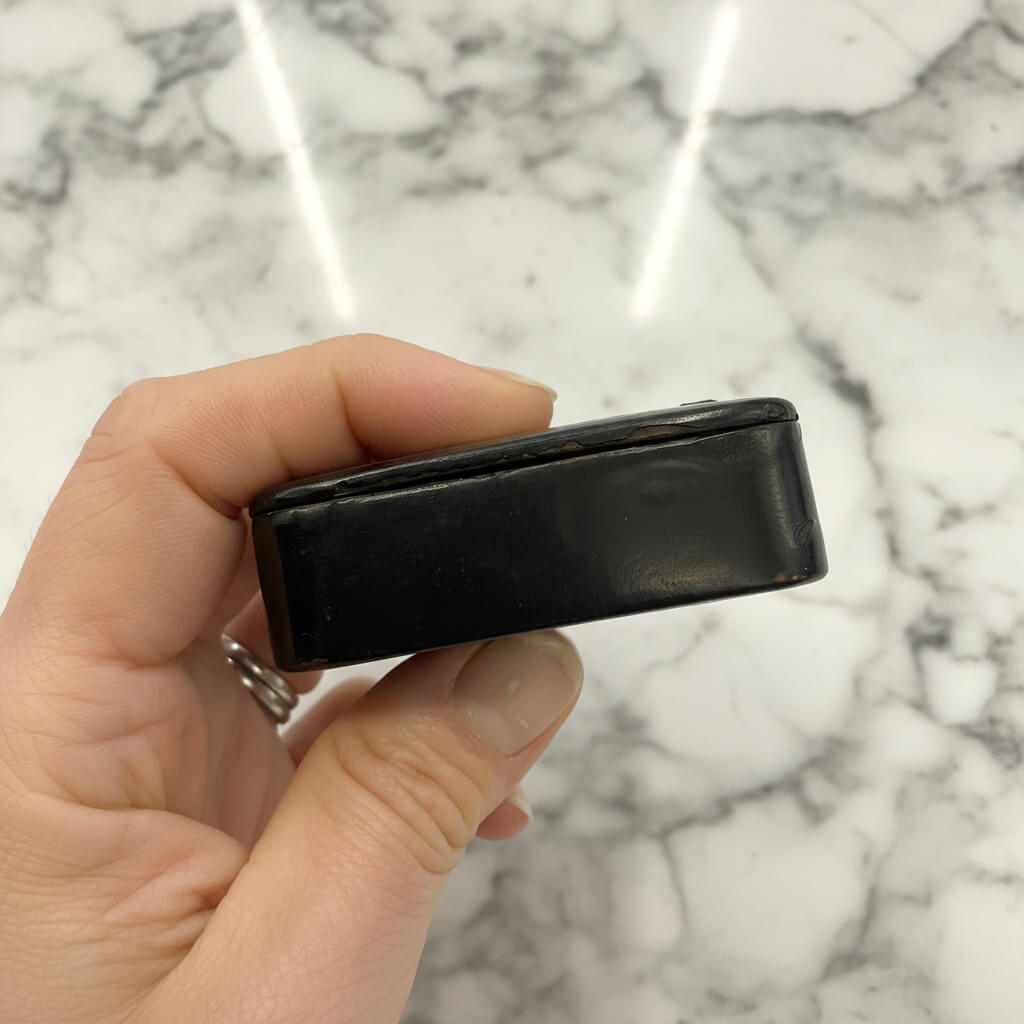 Hand holding a black rectangular box against a marble background