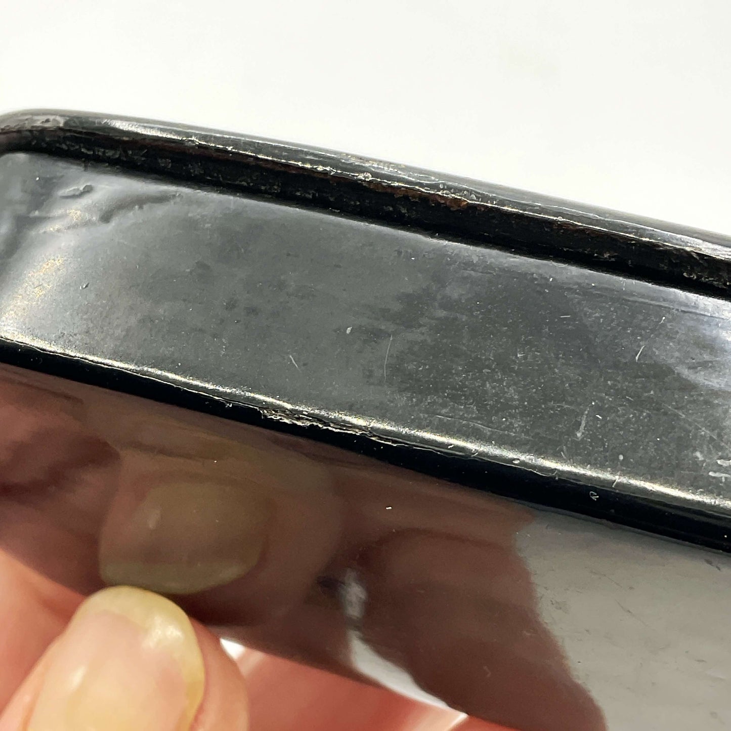 Close-up the edge of a trinket box with a hand holding it against a white background