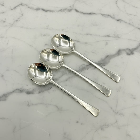three silver salt spoons on a marble surface