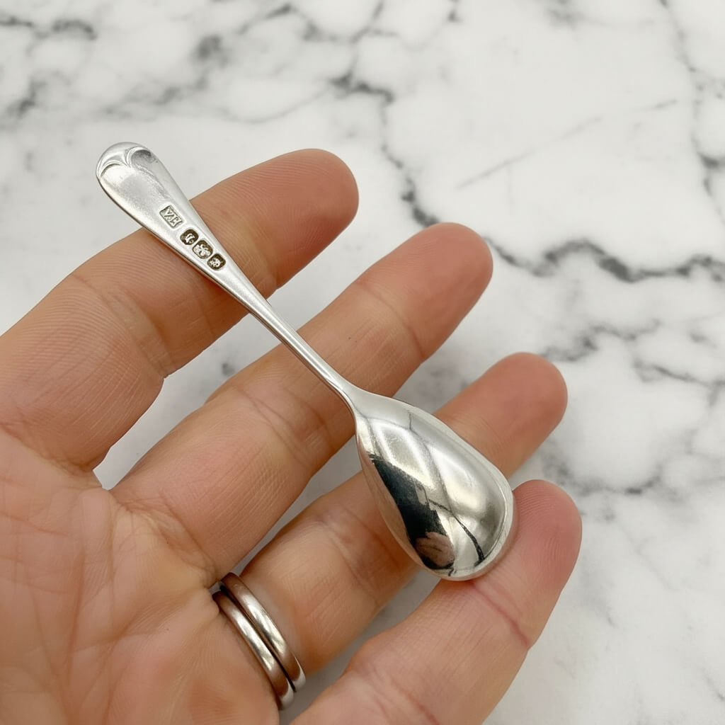 Silver spoon held in a hand with a marble background