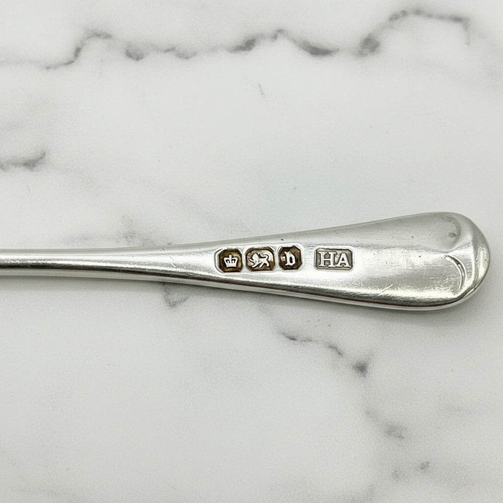 Silver spoon with engraved marks on a marble surface
