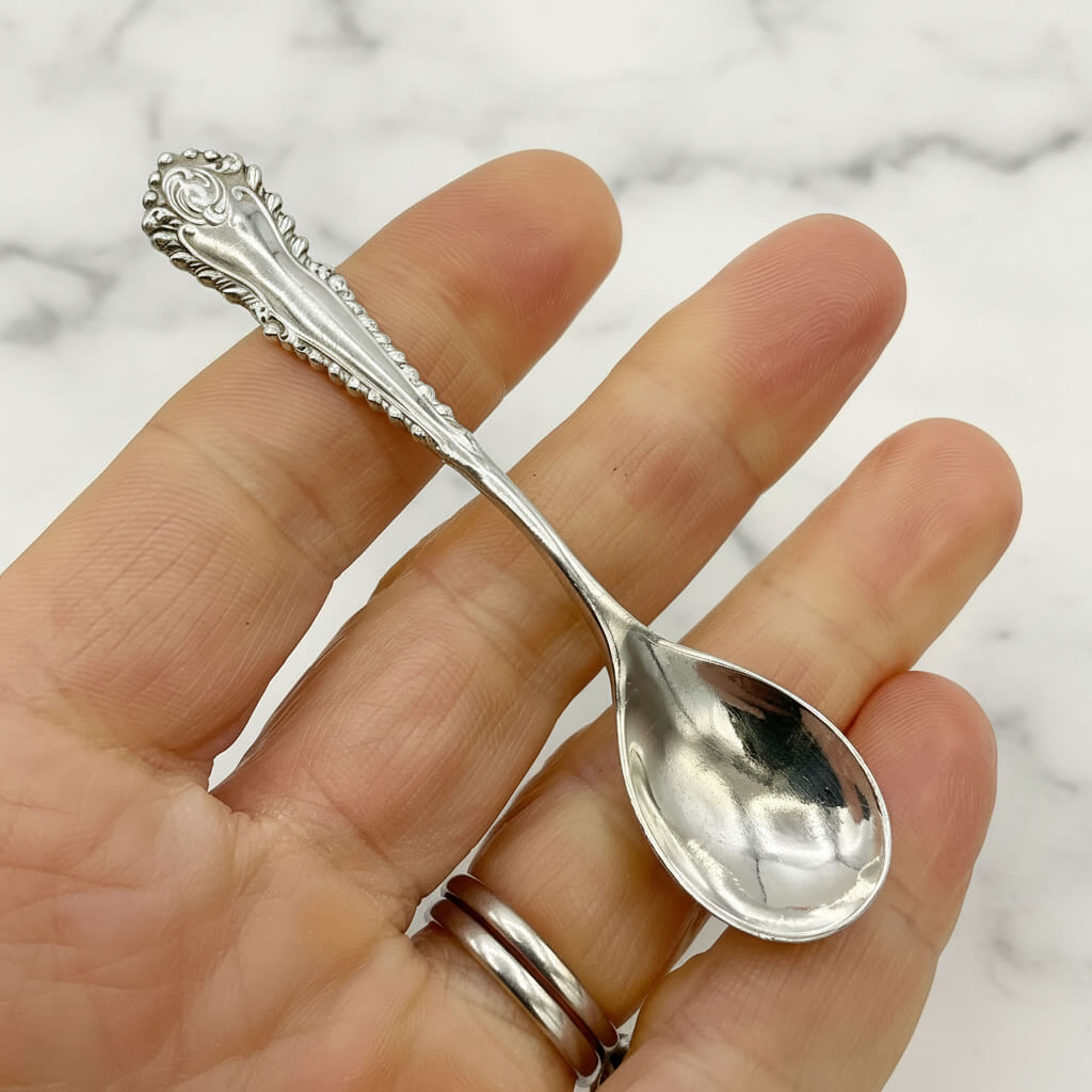 Silver spoon held in a hand against a marble background