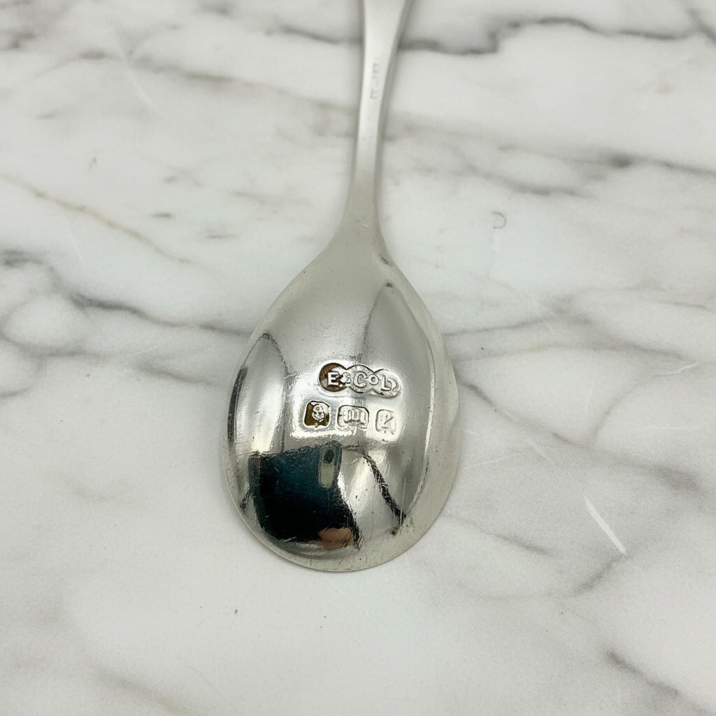 Silver spoon with visible hallmarks on a marble background