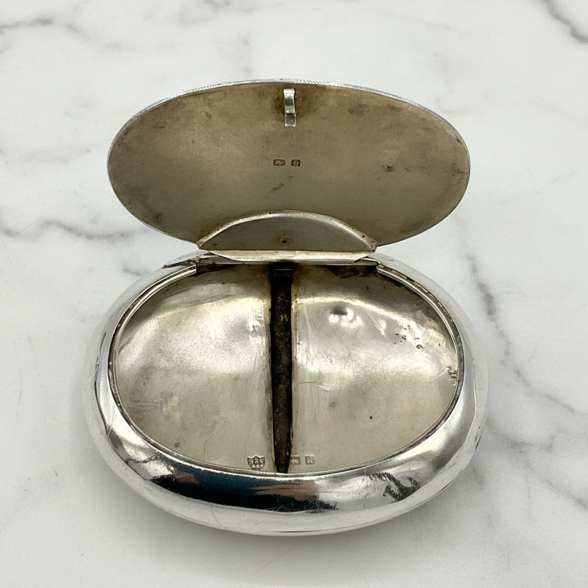 Silver box with lid open showing hallmarks on a marble worktop