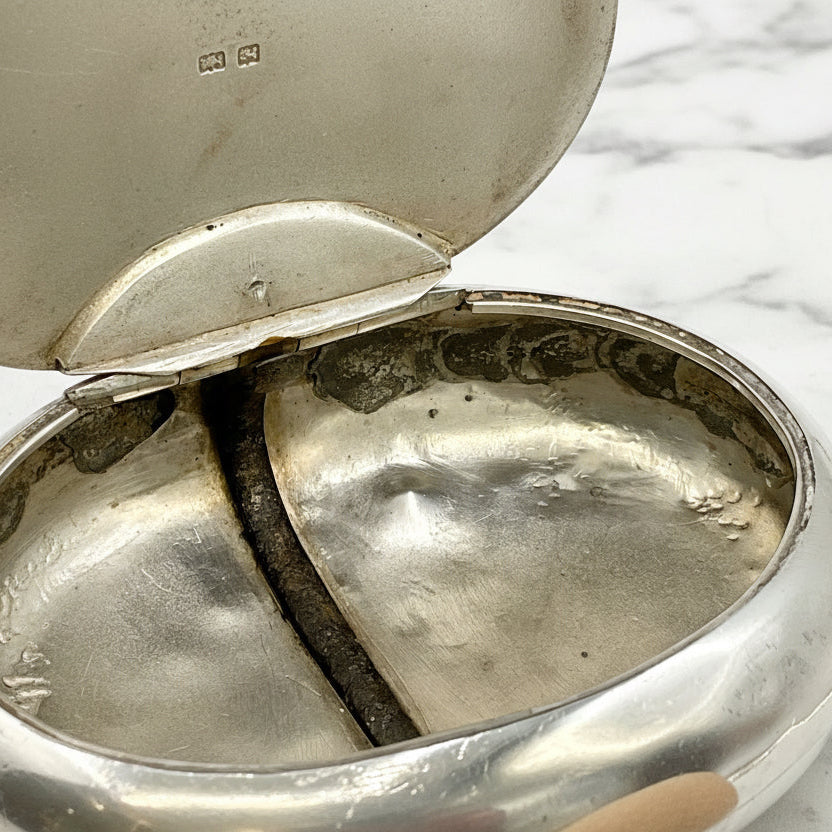 Silver box with open lid on a marble surface