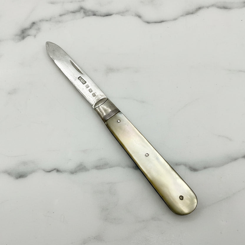 Antique fruit knife with a decorative handle on a marble surface