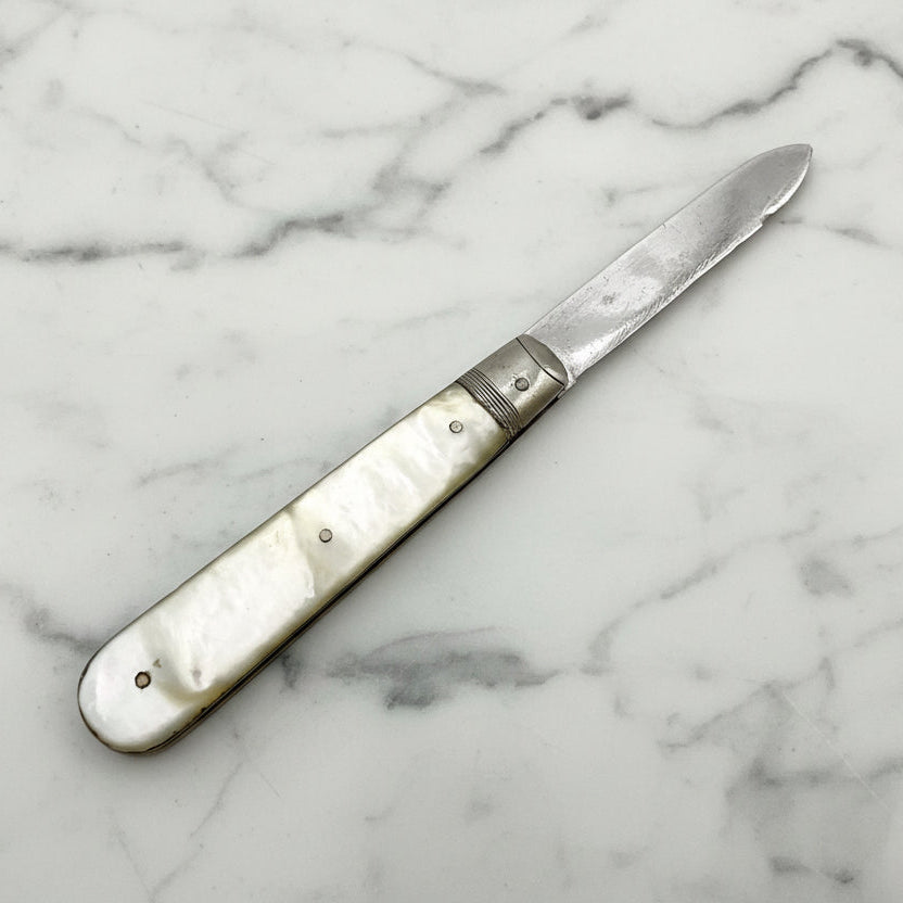 Antique fruit knife with mother-of-pearl handle on a marble surface