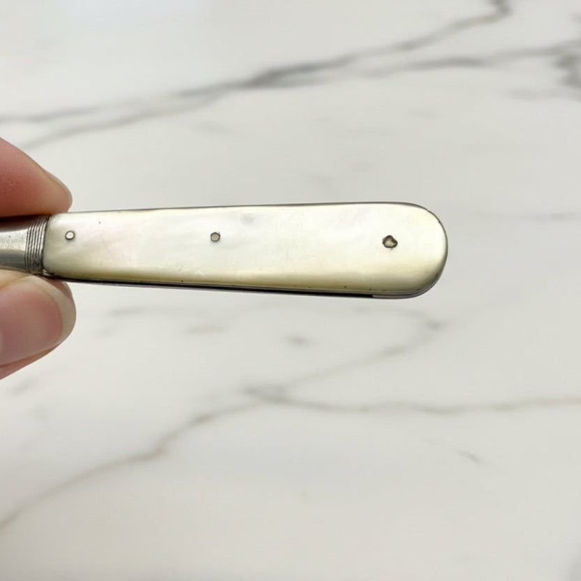 Fruit knife handle held by a hand against a marble background