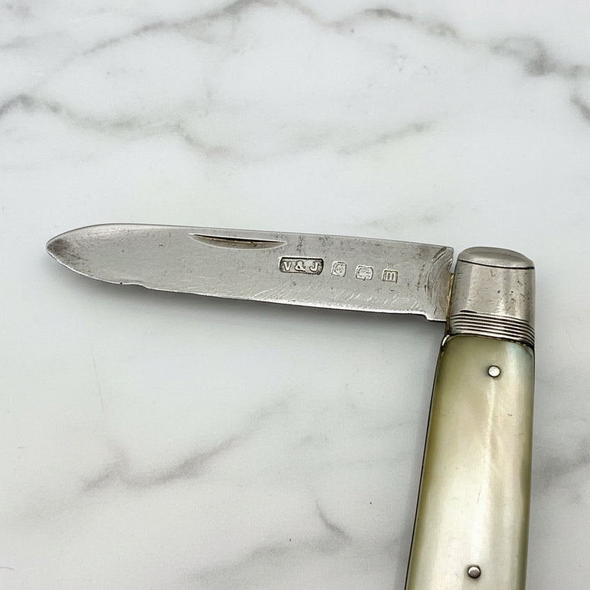 Antique fruit knife with a silver blade and pearl  handle on a marble background