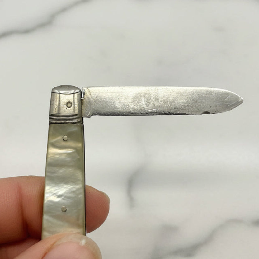Small fruit knife held by a hand against a marble background