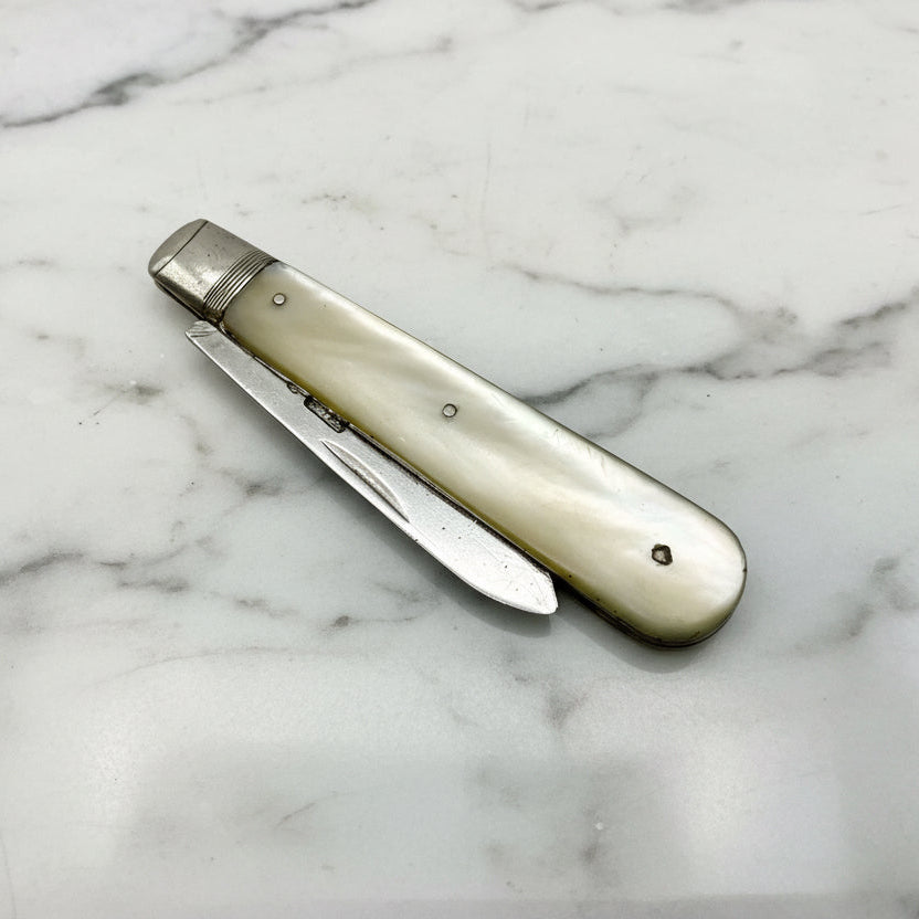 Folding knife with a pearl handle on a marble surface