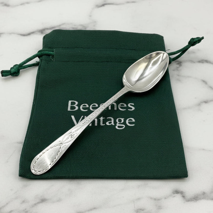 Silver spoon on a green drawstring bag with Beeches Vintage text.