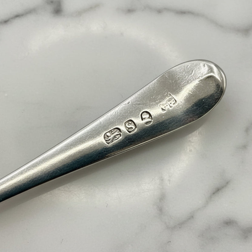 Silver spoon with hallmarks on a marble surface