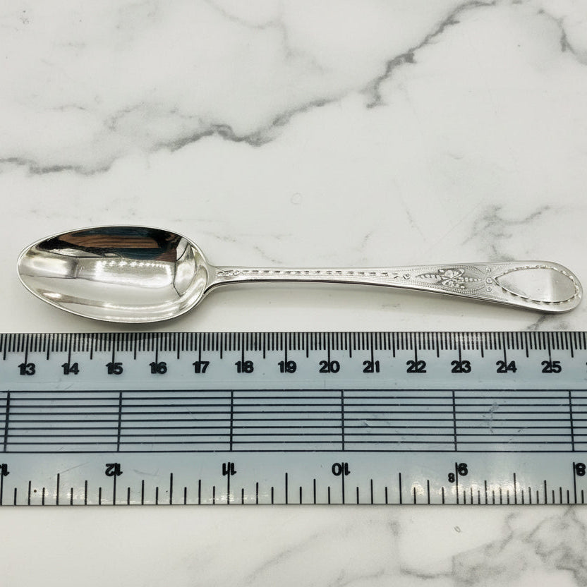 Silver spoon next to a ruler on a marble background