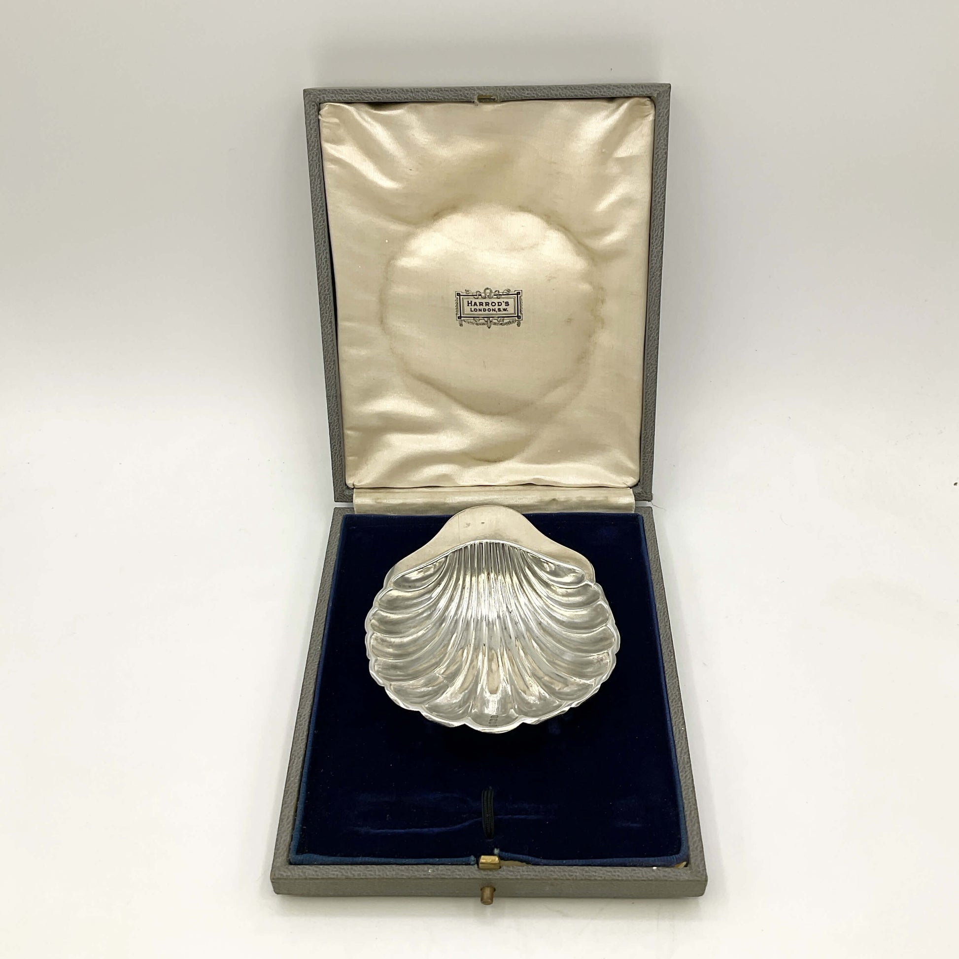 Silver shell-shaped object in a box on a marble surface