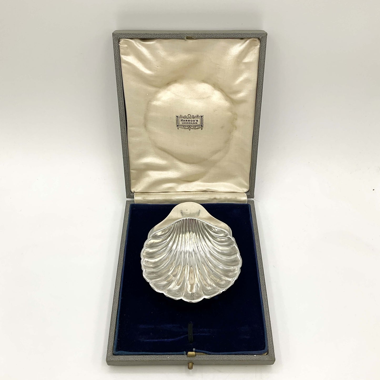 Silver shell decorative item in an open box on a marble surface