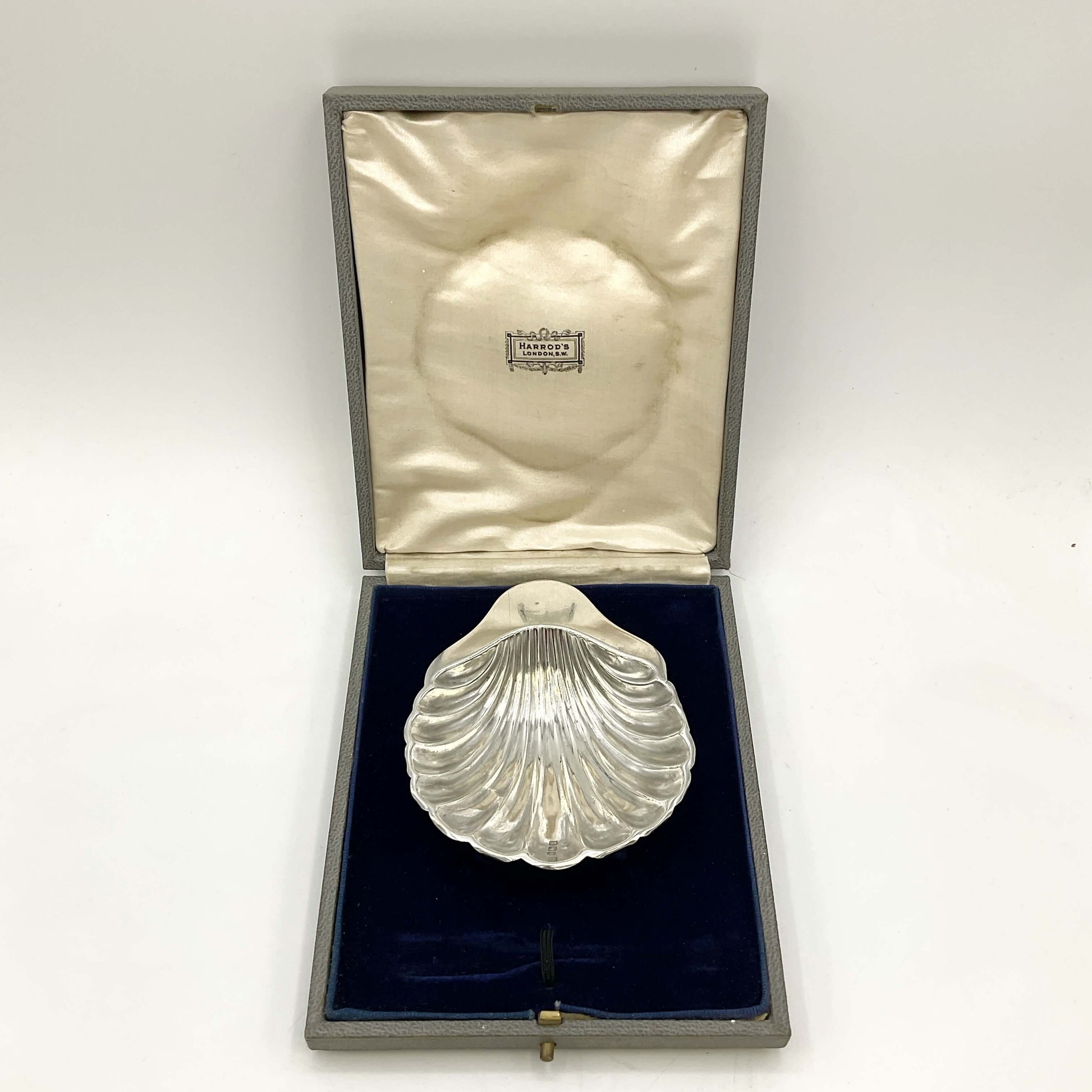 Silver shell decorative item in an open box on a marble surface