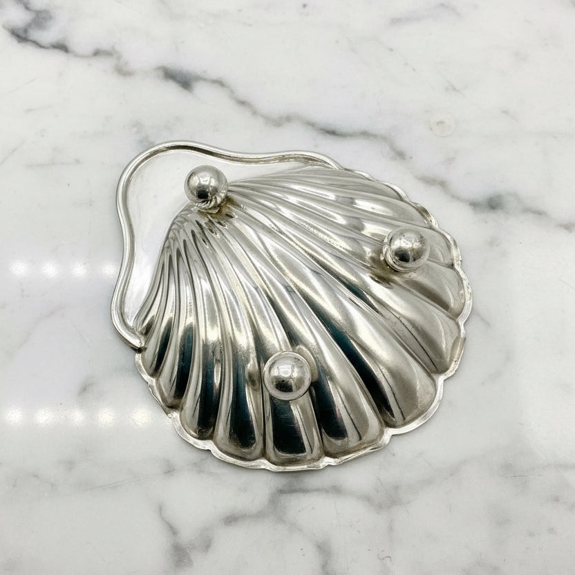 Silver shell-shaped dish upside down on a marble background