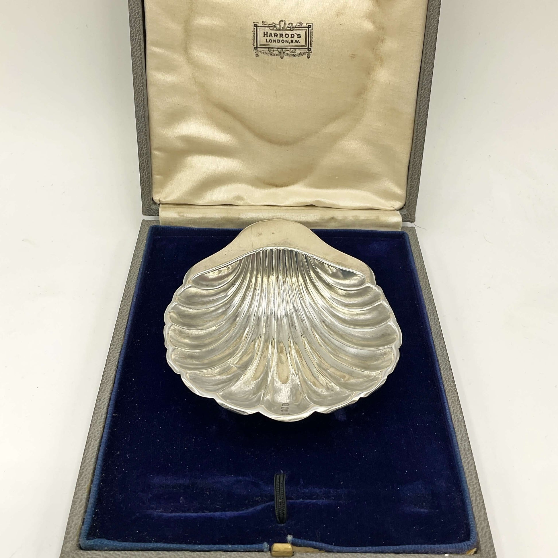 Silver shell-shaped object in a box with 'Harrods' branding.