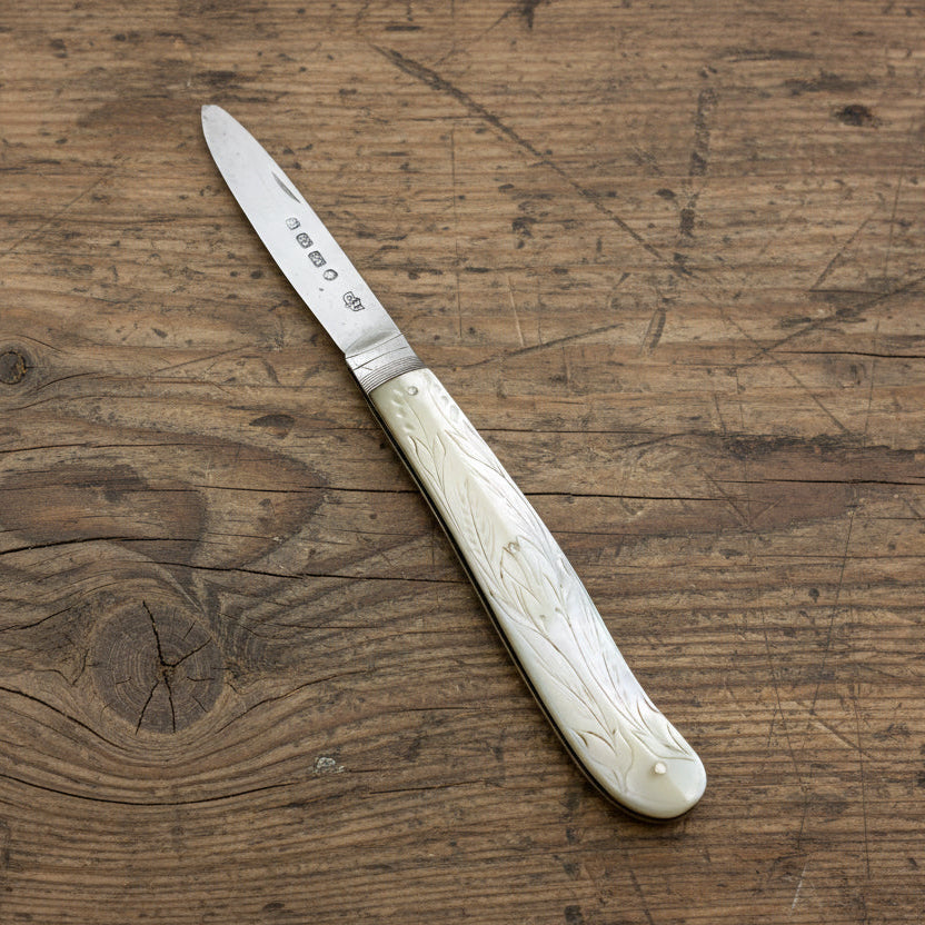 Antique fruit knife with a decorative handle on a wooden surface