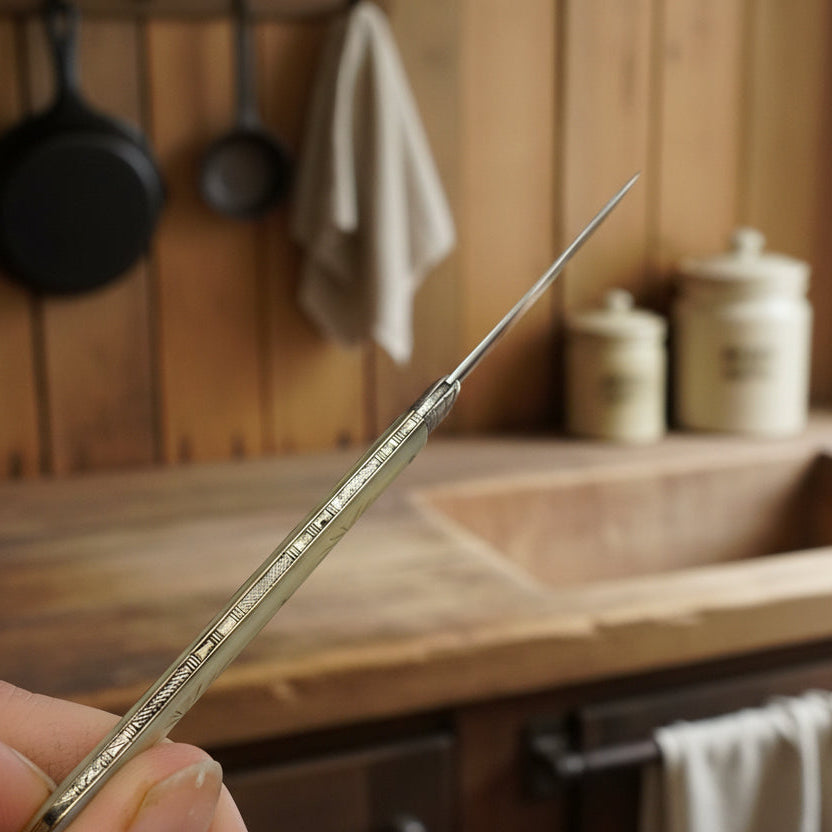 top of antique fruit knife in a hand with a rustic kitchen background