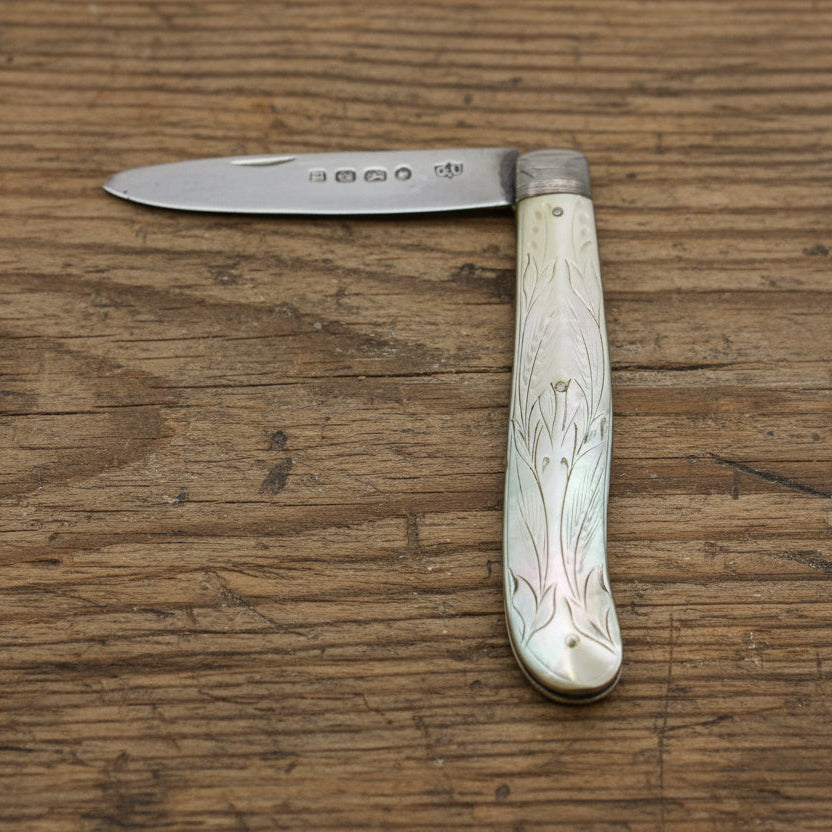 Antique pocket knife with decorative handle on a wooden surface