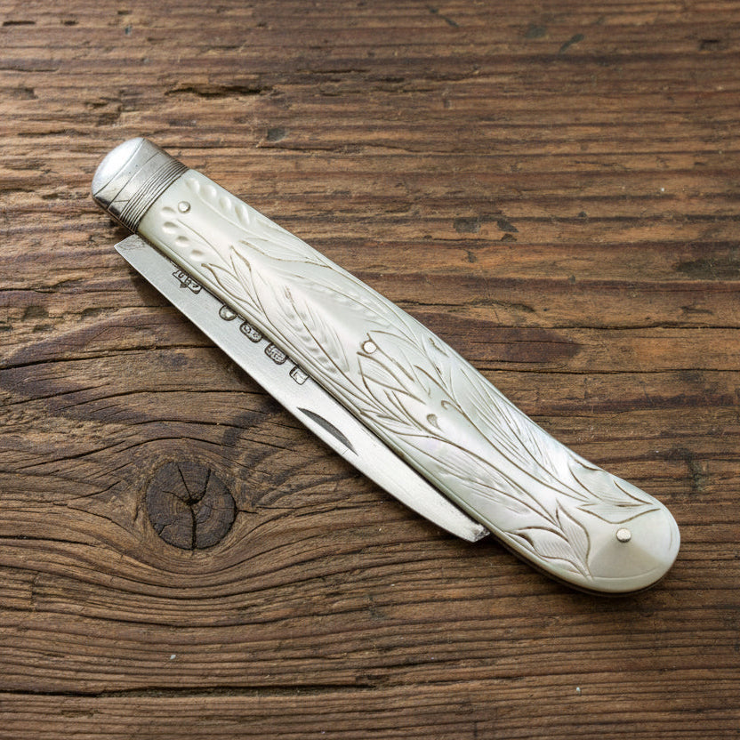 Decorative folding knife with engraved handle on a wooden surface