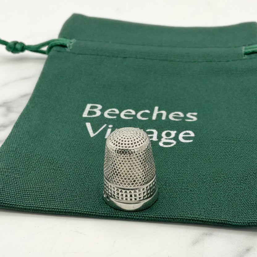 Silver thimble on a green fabric pouch with 'Beeches Vintage' branding.