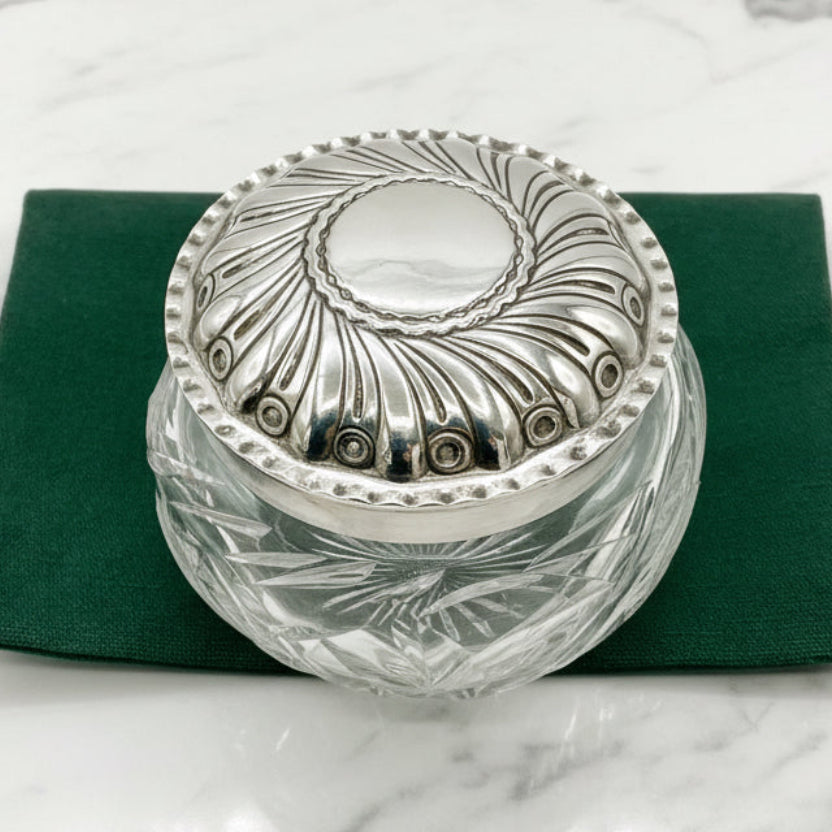 Silver-trimmed glass container on a green napkin with a white marble background