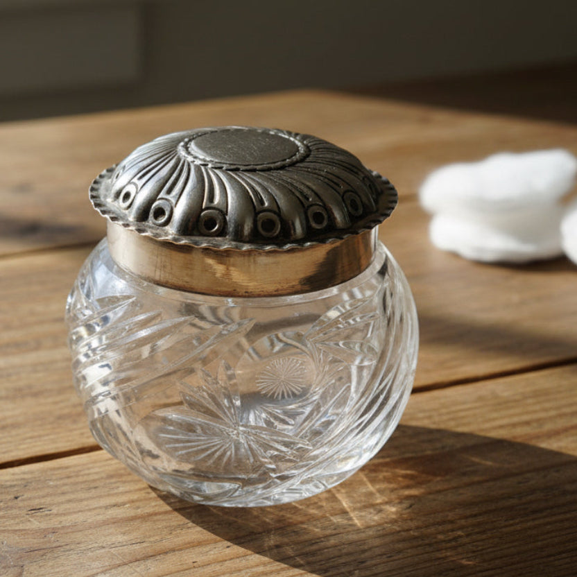 Clear glass jar with decorative silver lid on a wooden surface