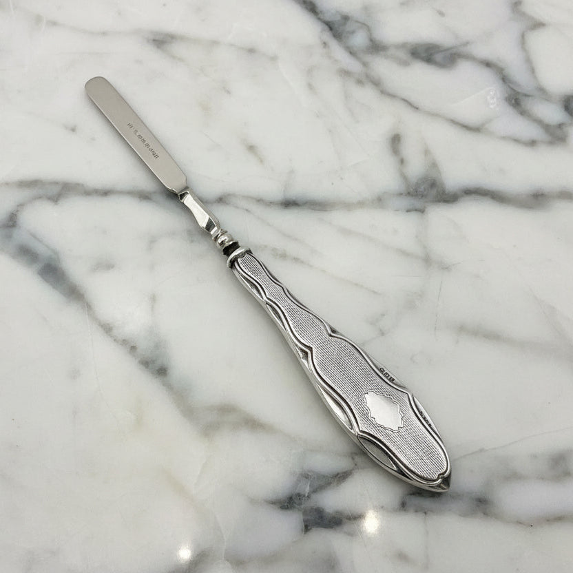 Silver cuticle pusher on marble