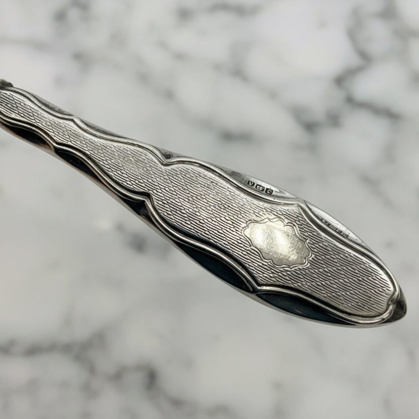 Close-up of a cuticle pusher with engraved design on a marble background