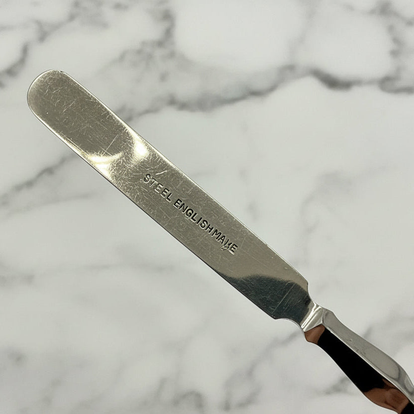 Silver cuticle pusher with 'Steel English Made' engraving on a marble background