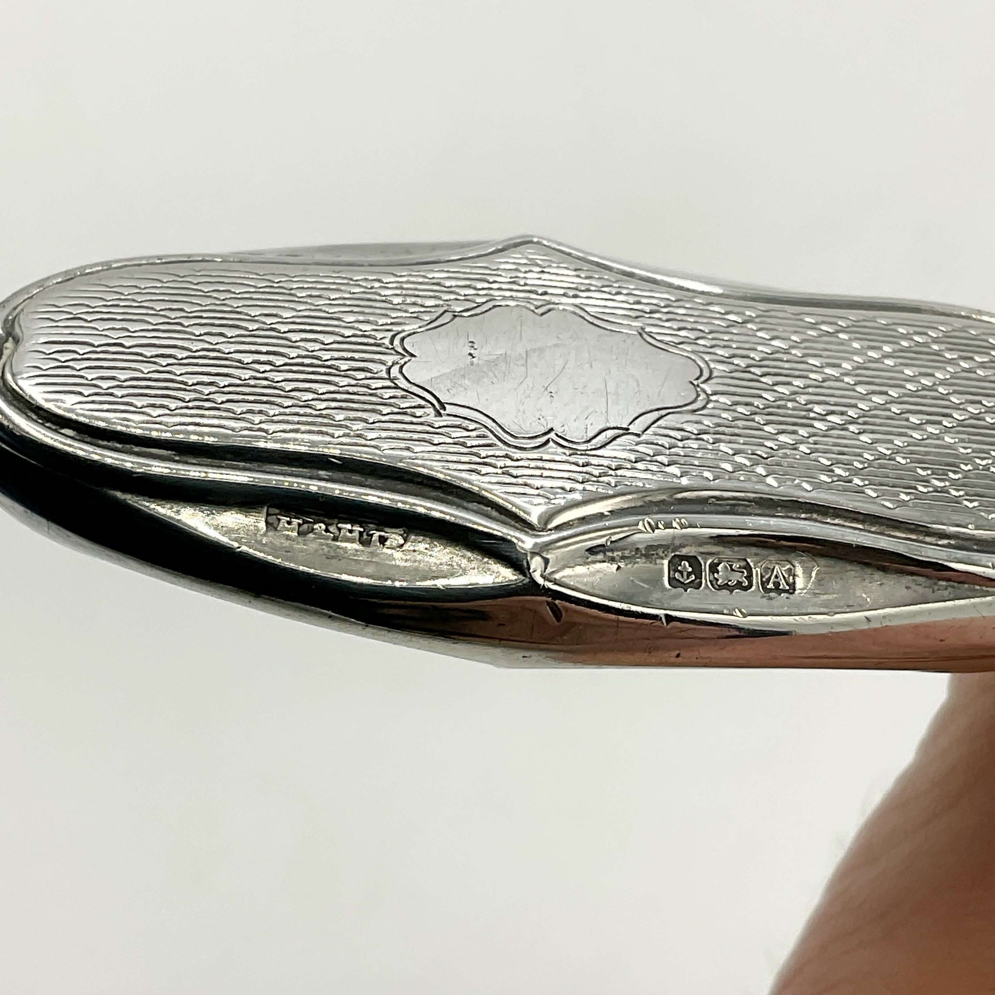 Silver cuticle pusher with hallmarks on a white background